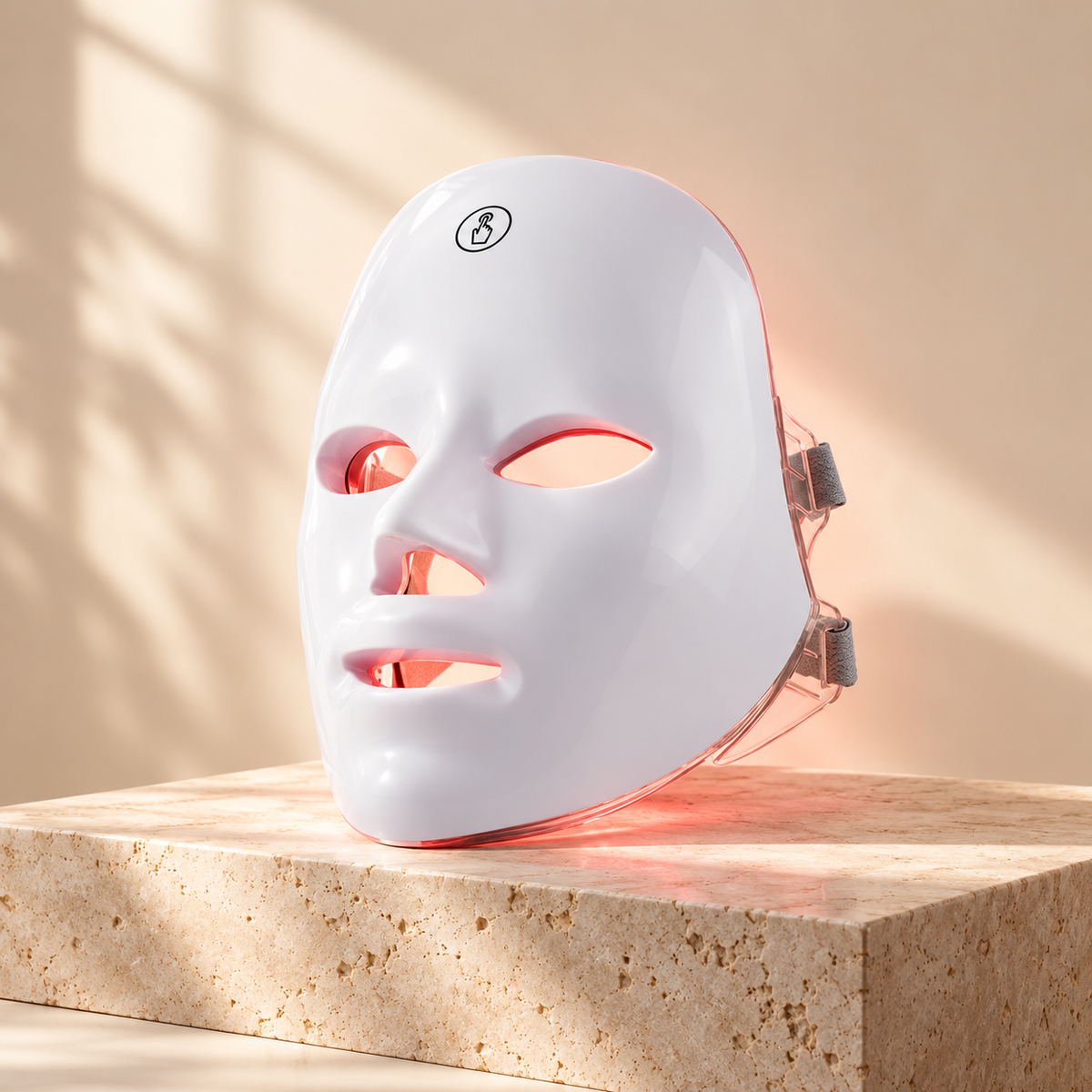 7-colour rechargeable LED face mask glowing red on a stone plinth